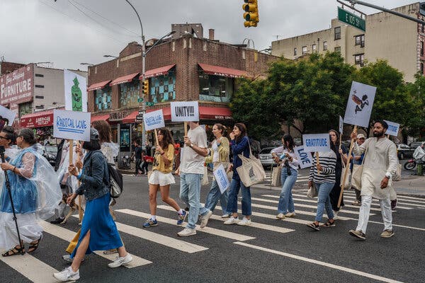 Walkers strike out on a march across Manhattan carrying signs that read “Radical Love,” “Gratitude,” “Love,” and “Unity!!!’’